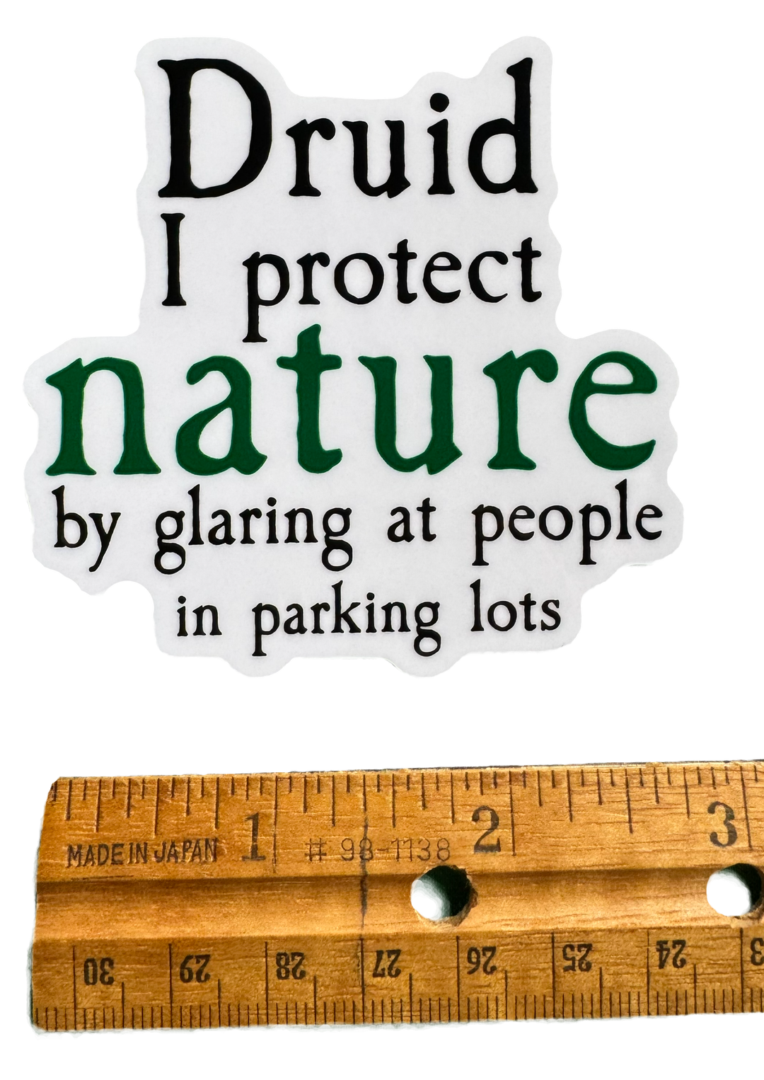 A bold, tongue-in-cheek design built around druid energy with attitude. The word Druid stands strong at the top, grounded in earthy style, followed by the phrase:

“I protect nature by glaring at people in parking lots.”

With a ruler for size Validity